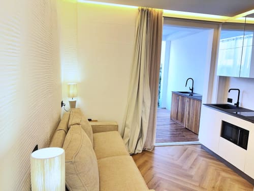 Interno di appartamento moderno con divano beige, zona cucina e accesso alla terrazza al La Sciumara Resort Palau