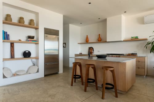 Modern kitchen with wooden island, bar seating, and open shelving at Casa Copal cottage in Isla Mujeres, Mexico