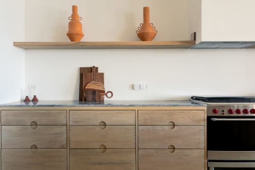 Modern kitchen with wooden cabinetry and open shelving displaying decorative wooden vessels at Isla Mujeres cottage