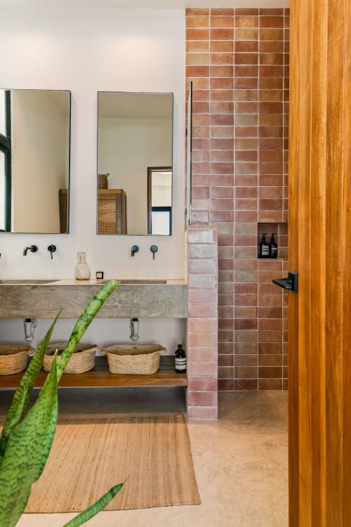 Modern Casa Copal bathroom at Isla Mujeres Realty featuring dual sinks, terracotta tile, concrete vanity, and ocean views.