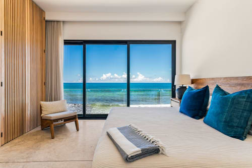 Beachfront bedroom at Casa Copal, Isla Mujeres with ocean views, blue pillows, and modern coastal design