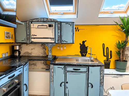 Cuisine colorée aux murs jaunes, armoires bleues et comptoirs noirs au Perchoir de Chaparon à Lathuile