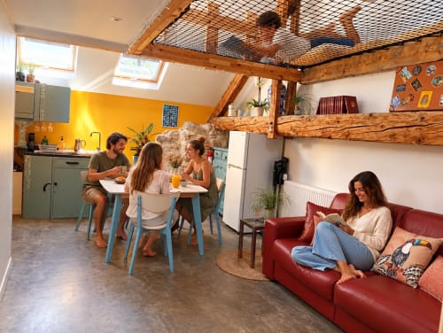 Espace de vie du Perchoir de Chaparon avec des clients dînant et se relaxant sur un canapé rouge dans ce gîte de montagne