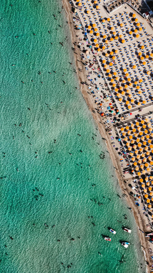 Vista aerea della spiaggia di Palermo con acque turchesi, ombrelloni gialli e barche ormeggiate vicino a Domus Fysi