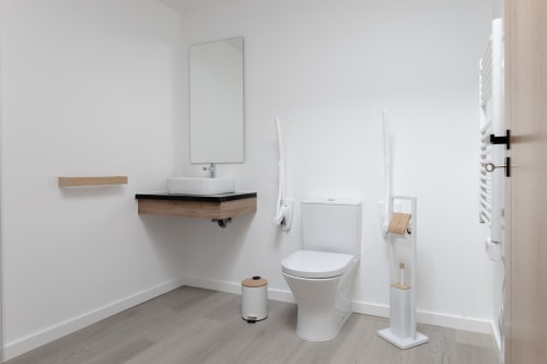 Banheiro moderno do hotel Recantos D'Almerinda em Pombal com vaso sanitário branco, gabinete de madeira e decoração minimalista