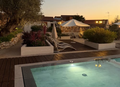 Piscina Recantos D'Almerinda ao anoitecer com terraço, espreguiçadeiras e casarões de pedra em Pombal