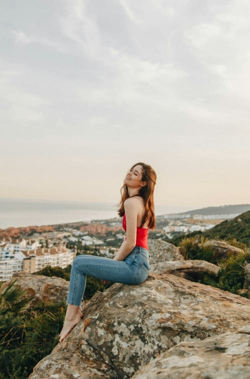 Donna in maglietta rossa affacciata sulla costa di Palermo da una collina rocciosa vicino a Domus Fysi