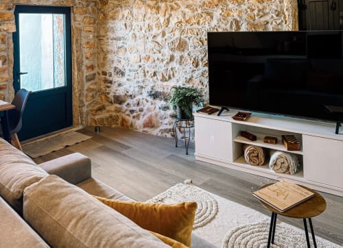 Sala de estar moderna do hotel Recantos D'Almerinda em Pombal com paredes de pedra, sofá bege, TV e porta de acesso à varanda