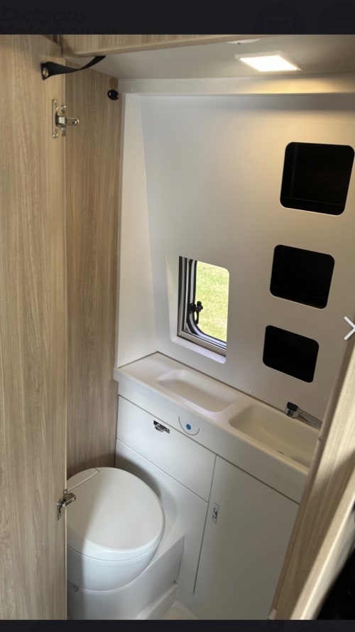 Compact bathroom in Weinsberg 4 berth campervan with toilet, sink, window, and storage shelves