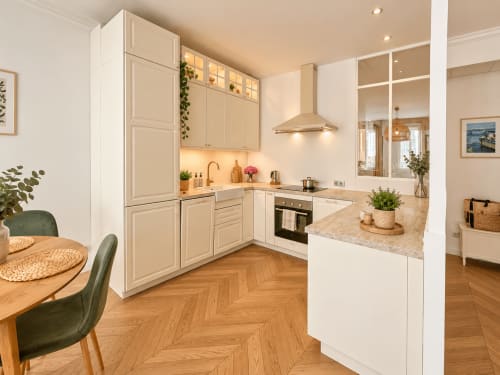 Cuisine blanche moderne avec comptoirs en marbre, parquet en chevrons et coin repas chez L'écrin de Pierre sur Mattbnb