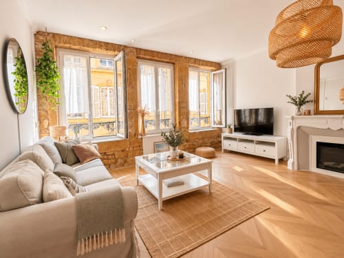 Lumineux salon moderne dans un appartement de Metz avec briques apparentes, canapé cuir, cheminée et vue sur la ville