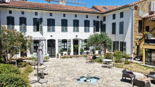 La Maison d'Augustin courtyard in Mont-de-Marsan with white colonial architecture, fire pit, and Mediterranean plants