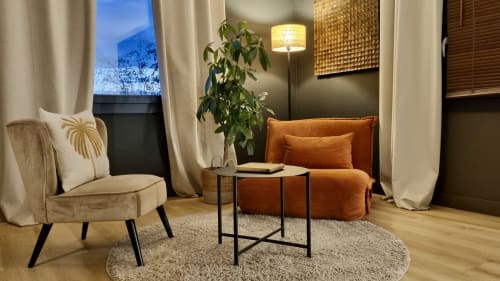 Salon moderne de La Villa Tonga B&B à Fronsac avec fauteuil beige, assise orange, plante en pot et éclairage chaleureux