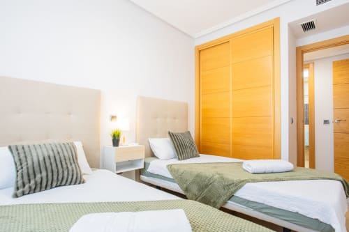 Moderno dormitorio con dos camas, cabeceras crema y toques verdes en Haus Holiday Homes, San Pedro del Pinatar