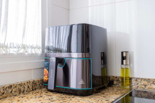 Freidora de aire moderna y dispensadores de aceite de oliva en encimera de granito en la cocina de Haus Holiday Homes, San Pedro del Pinatar