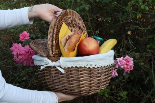 Cesto di vimini con frutta fresca e pane tra le mani vicino ai fiori rosa presso La Casa dei Tigli, Cannara