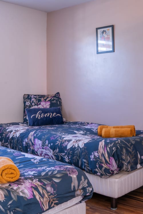 Acogedor dormitorio en la casa rural Les Ambrades de Colmar con camas gemelas, ropa de cama floral y toallas naranjas