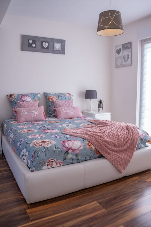 Elegante dormitorio en la casita La Vénitienne de Colmar con ropa de cama azul floral, almohadas rosas y decoración moderna
