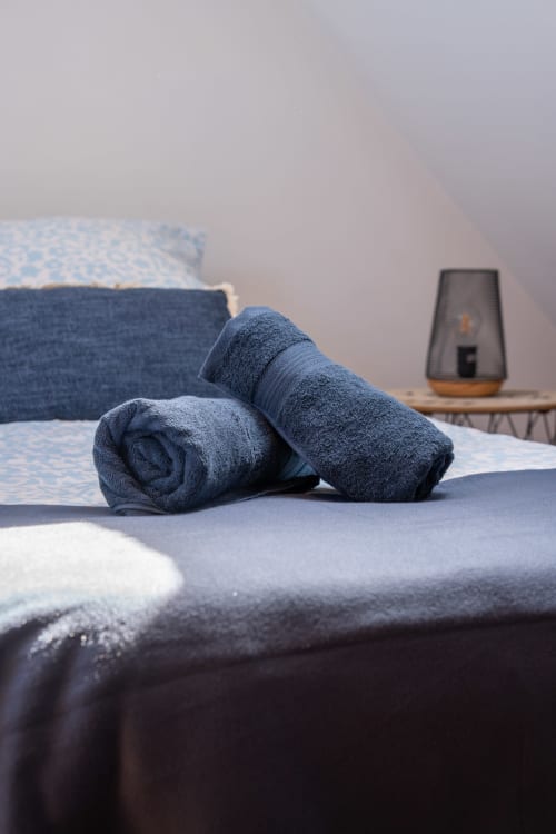 Toallas azules enrolladas en la cama de la casa rural Les Ambrades en Colmar, Francia