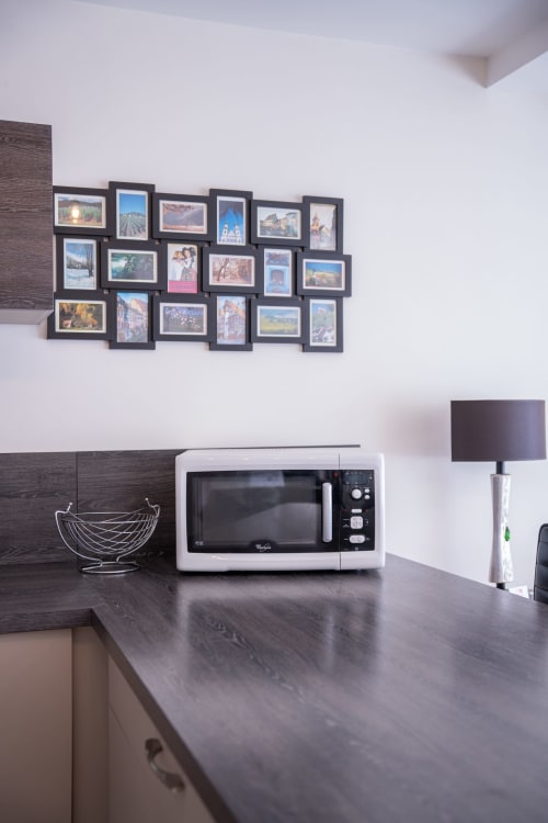 Encimera moderna con microondas en la casa rural Les Ambrades en Colmar, pared de galería con fotos de viajes