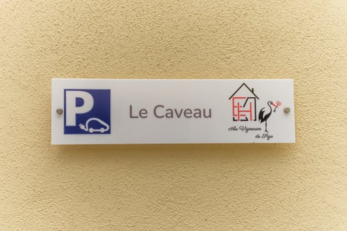Letrero Le Caveau con logo de aparcamiento y casa de viñedos en Les Ambrades, Kaysersberg-Vignoble
