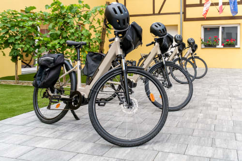 Fila de bicicletas eléctricas con cascos estacionadas frente a la casa rural Les Ambrades en Kaysersberg Vignoble, Francia
