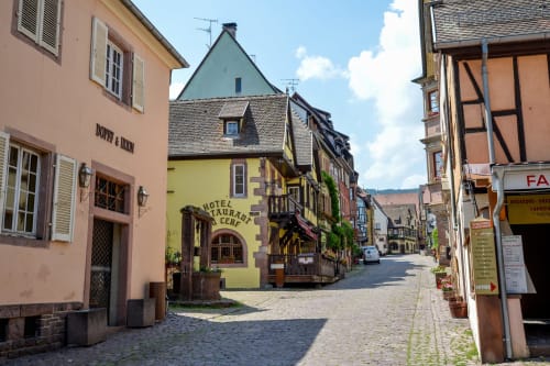 Encantadora calle empedrada en Riquewihr con edificios medievales coloridos y el Hotel Restaurant Cerf