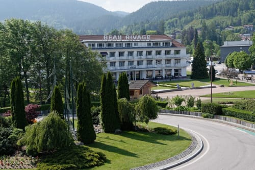Hotel Les Ambrades con jardines cuidados, cipreses y vistas a las montañas en Gérardmer, Francia