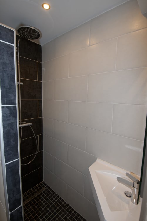 Baño moderno con alcachofa de ducha lluvia, acentos de azulejos negros y paredes de azulejos blancos tipo metro en la casa rural Les Ambrades en Gérardmer