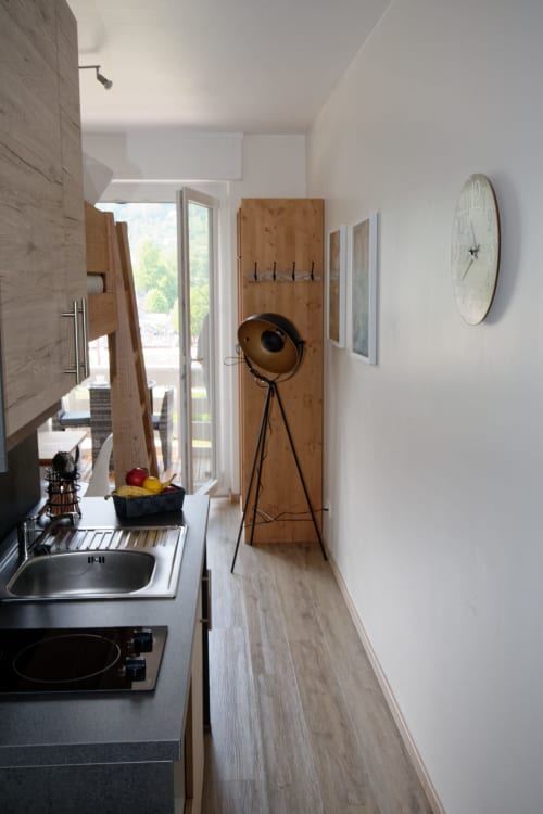 Cocina de galera moderna en la casa rural Les Ambrades con fregadero, fogones, almacenamiento y pared de acento de madera con lámpara trípode