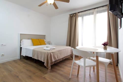 Dormitorio moderno en Apartamentos El Sol II en Tossa de Mar con cama, almohadas amarillas, escritorio blanco y ampla luz natural