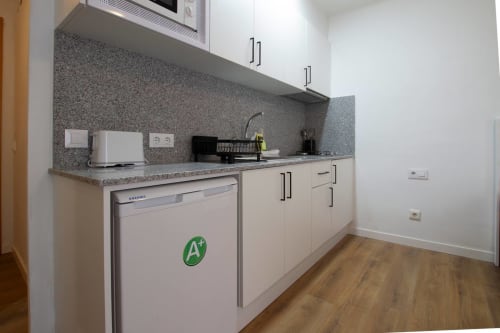 Cucina moderna dell'appartamento agli Apartamentos El Sol II a Tossa de Mar con armadi bianchi, piano cottura in granito e