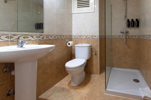 Bagno moderno negli Apartamentos El Sol II, Tossa de Mar con piastrelle, lavabo, water e doccia aperta