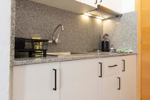 Cocina moderna con encimera de granito y muebles blancos en Apartamentos El Sol II, Tossa de Mar