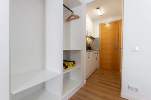 Pasillo moderno de Apartamentos El Sol II Tossa de Mar con cocina americana, puerta de madera, estanterías blancas