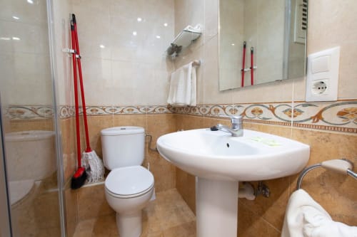 Baño moderno en Apartamentos El Sol II, Tossa de Mar, con lavabo blanco, inodoro, ducha y azulejos decorativos