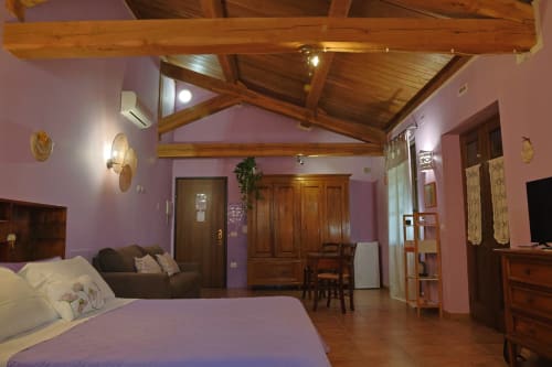 Camera Lilla della Casa dei Tigli a Cannara: travi in legno a vista, pareti rosa, letto, zona living e arredamento in legno