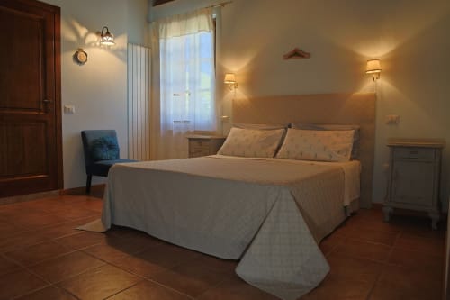 Camera da letto Azzurro a La Casa dei Tigli a Cannara con letto matrimoniale, pavimenti in terracotta, finestre con vista sul giardino e accogliente