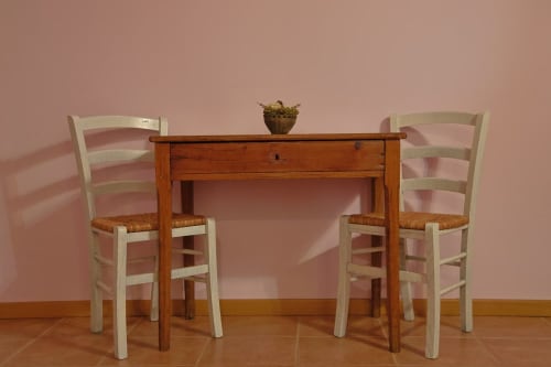 Rustico tavolo in legno con due sedie a scala color crema e sedute intrecciate nell'appartamento di La Casa dei Tigli, Cannara