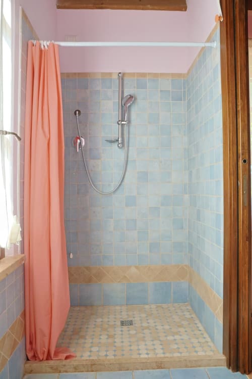 Moderno bagno con pareti rivestite in piastrelle blu e tenda corallo presso l'appartamento La Casa dei Tigli a Cannara