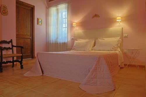 Elegante camera da letto di La Casa dei Tigli B&B a Cannara con pareti rosa, biancheria color crema e illuminazione calda