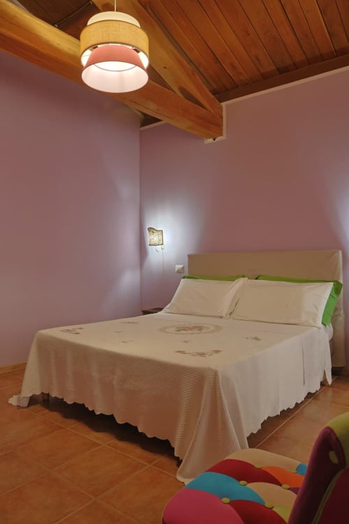 Camera moderna di La Casa dei Tigli B&B a Cannara con pareti rosa, travi in legno e letto confortevole