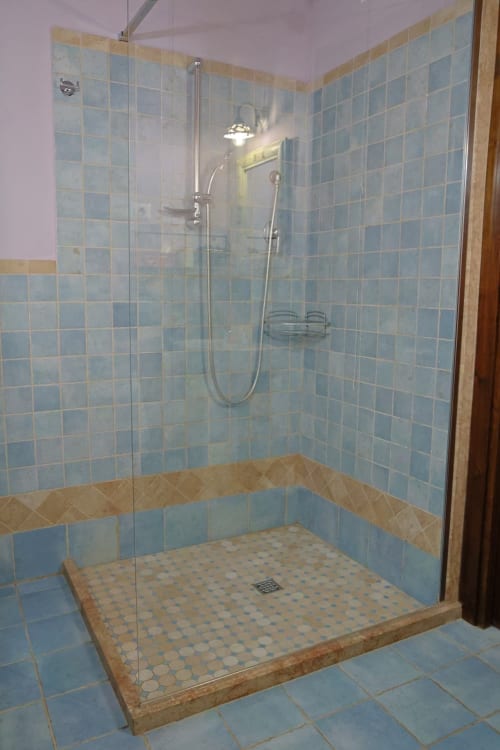 Moderna doccia walk-in con piastrelle blu e soffione pioggia presso La Casa dei Tigli, appartamento a Cannara