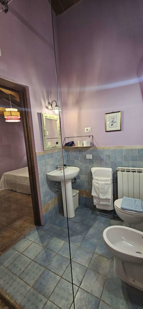 Bagno moderno in Appartamento Malva a La Casa dei Tigli, Cannara, con pareti viola, dettagli in piastrelle blu e vetro