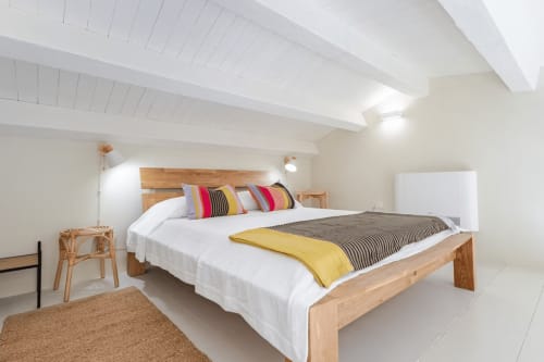 Camera da letto luminosa e moderna a Case Luparello con letto in legno, cuscini colorati, travi bianche e vista sul giardino
