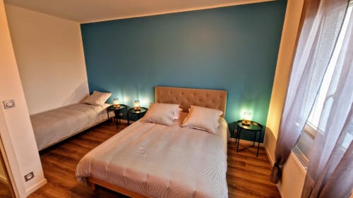 Chambre moderne avec lit queen-size, mur d'accent bleu-vert, luminosité chaleureuse et parquet au cottage Vindihouses à Magnien