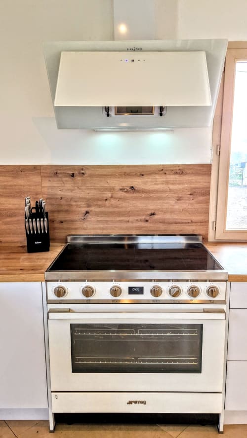 Cuisine moderne avec cuisinière blanche et plaque de cuisson en acier inoxydable sous une hotte blanche dans le gîte Magnien