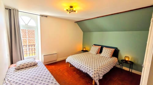 Spacious bedroom at Vindihouses La Villa 1848 in Épinac with two beds, green accent wall, and balcony access