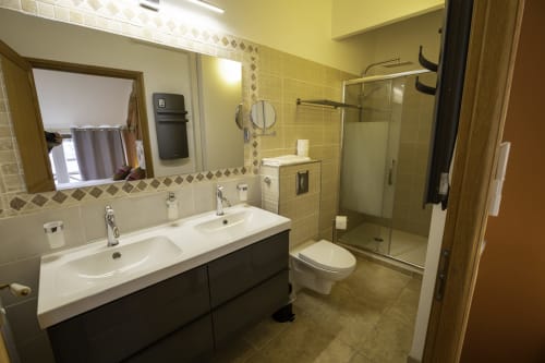 Salle de bain moderne au Domaine Chapelle B&B avec double vasque, douche à l'italienne et accents de carrelage jaune