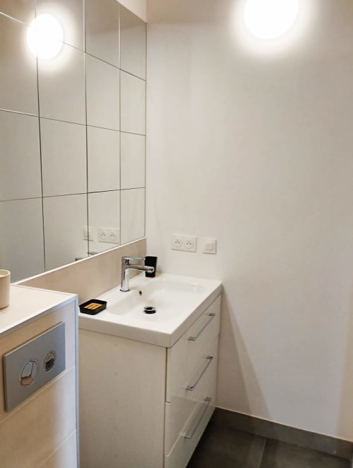 Salle de bain moderne au Domaine Chapelle B&B avec vasque blanche, robinetterie chromée, grand miroir et éclairage optimal